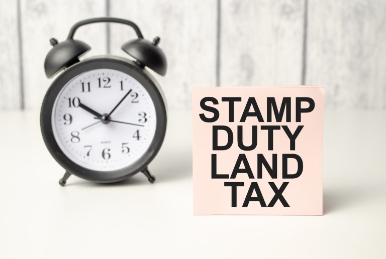 The word stamp duty land tax written on pink sticker and alarm clock